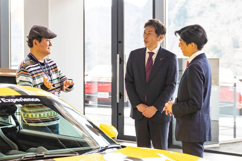 ポルシェセンター千葉・店長の山崎渉（中）、セールスコンサルタントの明賀則和（右）と談笑する本庄さん。